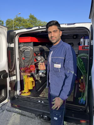Mitarbeiter von Andres Gabelstapler vor einem weißen Transporter mit einem Akkuschrauber in der Hand.