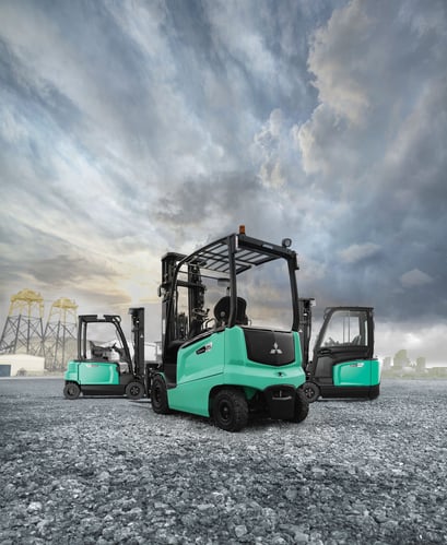 Drei türkisfarbene Gabelstapler von Mitsubishi auf einem Industriegelände unter bewölktem Himmel. Drei türkisfarbene Gabelstapler von Mitsubishi auf einem Industriegelände unter bewölktem Himmel.